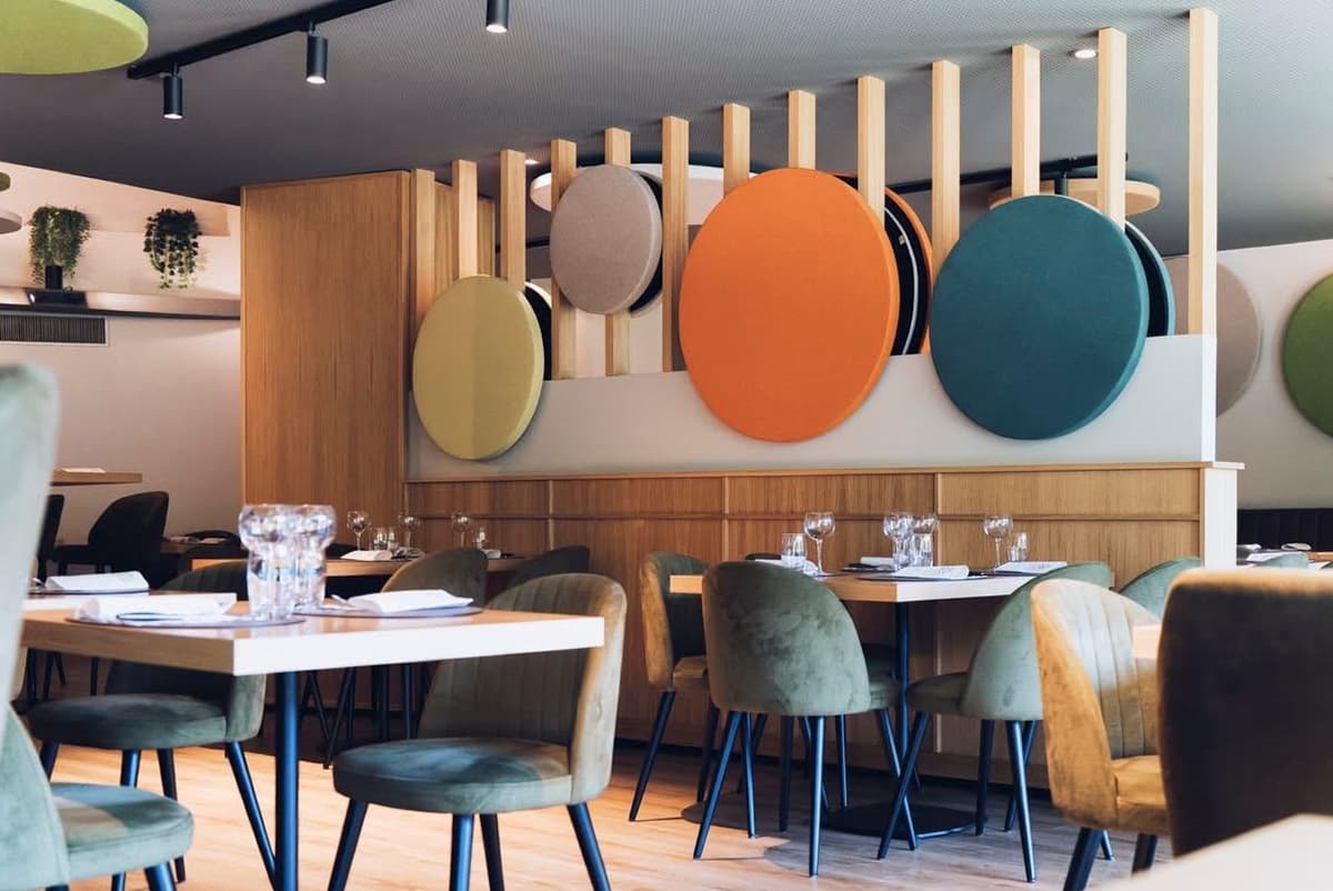 Soluzioni di fonodesign a parete con pannelli acustici circolari custom LvB Italia, realizzati senza stampi industriali per preservare la densità della fibra.